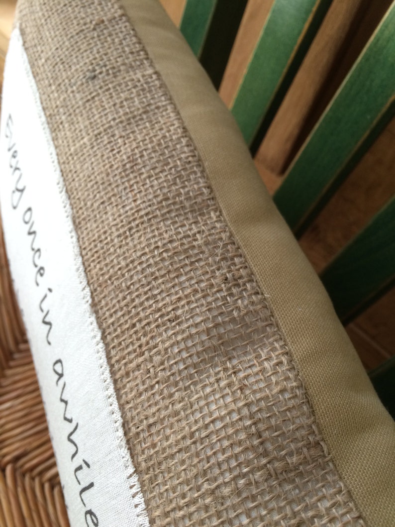 May include: A close-up of a beige pillow with a burlap trim and the text "Every once in awhile" printed on the front.