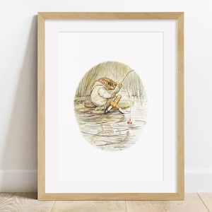 Könnte beinhalten: Eine gerahmte Illustration eines Frosches, der ein weißes Hemd und eine weiße Hose trägt, auf einem Seerosenblatt sitzt und mit einer Angelrute angelt. Der Frosch ist von Wasser und Schilf umgeben, und im Wasser schwimmen Fische.