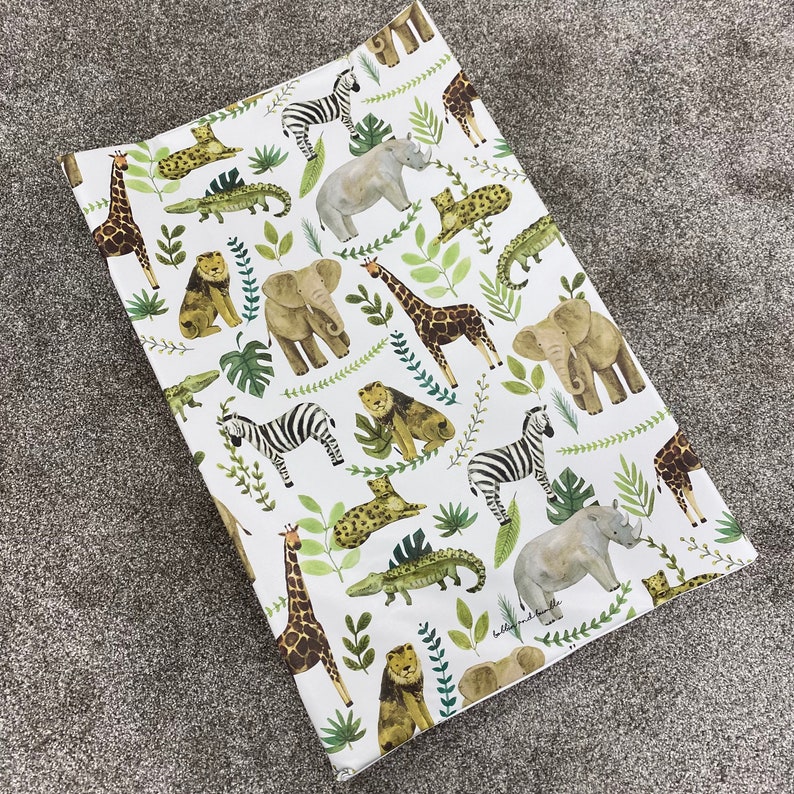 K&ouml;nnte beinhalten: Wei&szlig;er Wickelauflagenbezug mit einem Dschungeltier-Druck. Der Druck zeigt Zebras, Elefanten, Giraffen, Nash&ouml;rner, Krokodile, L&ouml;wen und eine Vielzahl von gr&uuml;nen Blattpflanzen.