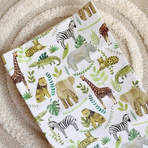 K&ouml;nnte beinhalten: Wei&szlig;er Stoff mit einem sich wiederholenden Muster aus verschiedenen Tieren, darunter Zebras, Giraffen, Elefanten und Nash&ouml;rner. Die Tiere sind im Cartoon-Stil mit gr&uuml;nem Laub und Bl&auml;ttern illustriert.