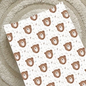 May include: White wrapping paper with a repeating pattern of brown bear faces and small floral designs. The bears are drawn in a simple, cartoon style.