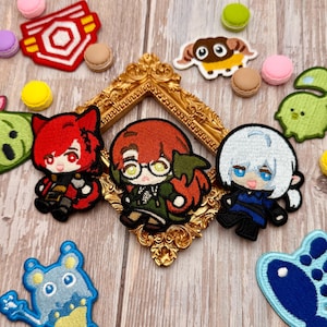 May include: A collection of embroidered patches featuring three anime-style characters, a red and white geometric emblem, a brown ram, a green creature, a blue creature, and a blue fish shape, arranged around a small gold ornate frame.