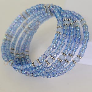 May include: A multi-strand bracelet made of iridescent blue beads and silver spacer beads. The bracelet is wrapped around the wrist multiple times.