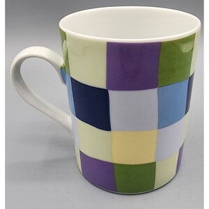May include: A white ceramic mug with a checkered pattern in shades of purple, green, blue, and yellow.