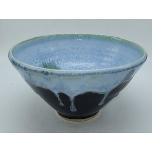 May include: A blue and black ceramic bowl with a drip glaze. The bowl has a wide rim and a rounded bottom.