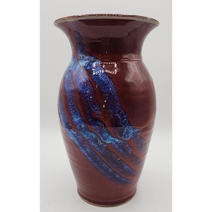 May include: A red and blue ceramic vase with a wide mouth and a narrow base. The vase has a mottled glaze with streaks of blue.