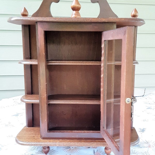 Vintage wall curio cabinet or free-standing. One glass door swings open to the right. 3 corner shelves on both sides & three shelves inside.