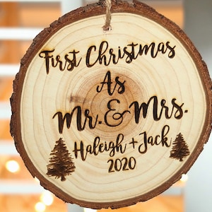 May include: A wooden Christmas ornament with the text "First Christmas as Mr. & Mrs.  Haleigh + Jack 2020" and two small pine tree designs.