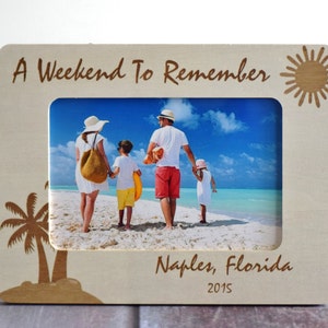 May include: Wooden photo frame with the text "A Weekend To Remember" and "Naples, Florida 2015". The frame features a picture of a family on a beach. The frame has a sun and palm tree design.