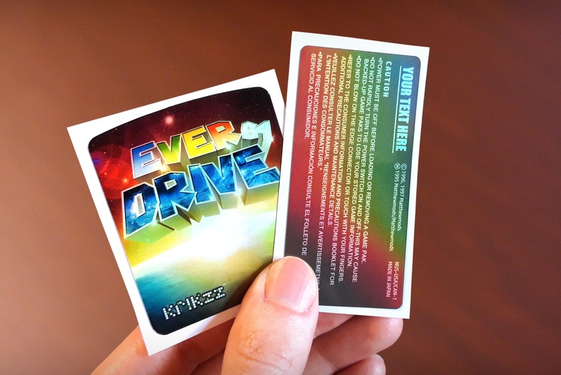 Op de afbeelding: Een sticker met een kleurrijk, 3D-ontwerp van de woorden "Ever Drive" op een achtergrond van een sterrenstelsel met sterren en planeten. De sticker is wit met een zwarte rand en de woorden "Krikzz" zijn onderaan in wit gedrukt.