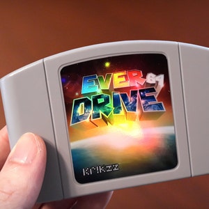 Op de afbeelding: Een grijze Nintendo 64-gamecartridge met een kleurrijk label met de tekst "EVERDRIVE" in 3D-stijl. Het label heeft ook een kleurrijke, abstracte achtergrond.