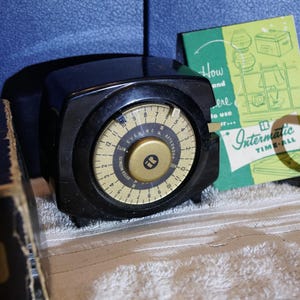 May include: A black Intermatic time-all timer with a gold-colored dial. The dial has numbers and the words "Evening" and "Afternoon". A green and white instruction card is visible. The timer is on a white surface.