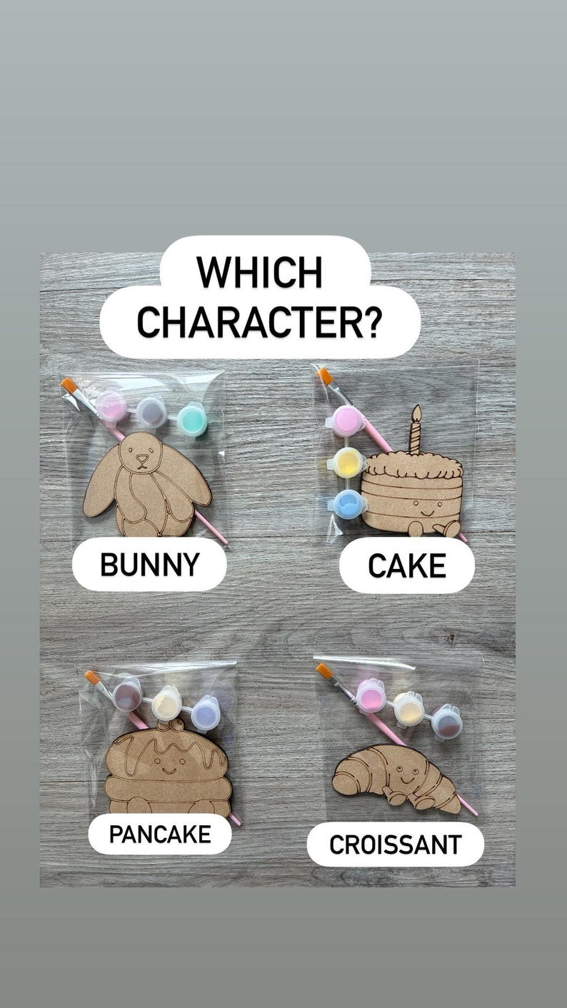 May include: Four individual craft kits in clear plastic bags, each containing a wooden cutout of a bunny, cake, pancake, or croissant, along with a small paintbrush and three small paint pots. The text "WHICH CHARACTER?" appears at the top.
