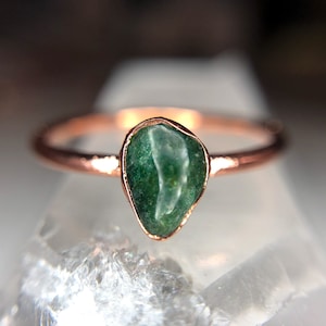May include: A ring with a green gemstone set in a rose gold band.
