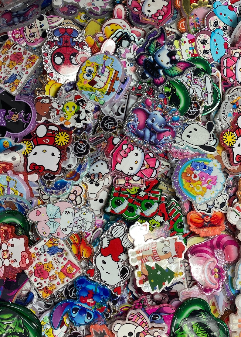 May include: A large collection of colourful acrylic character charms featuring various cartoon figures including Hello Kitty, SpongeBob SquarePants, Dumbo, Snoopy, and Care Bears. Each piece has a glittery finish and distinct printed designs.