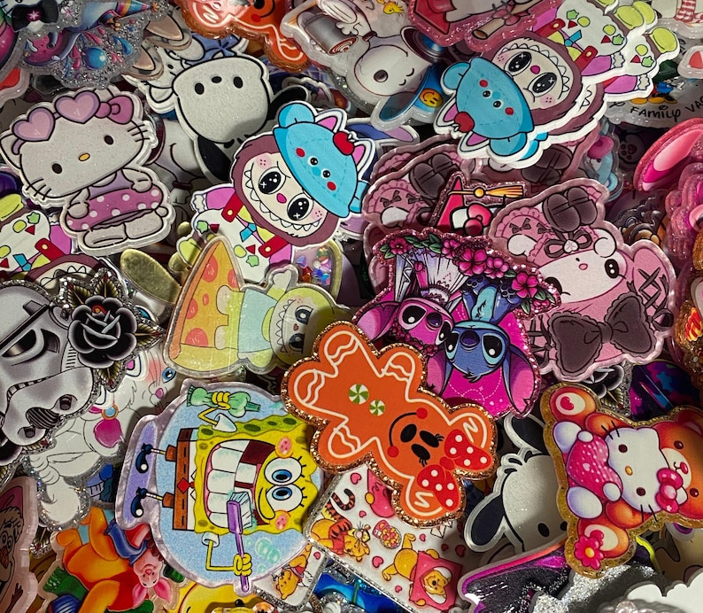 May include: A collection of assorted acrylic character charms featuring various cartoon figures including Hello Kitty, SpongeBob SquarePants, Stitch, and a gingerbread man. Each charm has a glossy finish with glitter accents and vibrant colours.