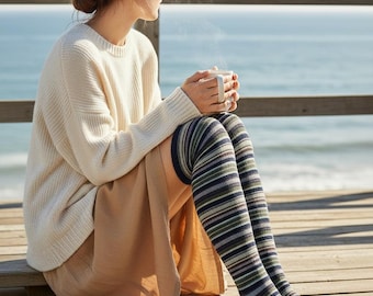 May include: Thigh-high socks featuring a horizontal striped pattern in shades of navy blue, olive green, light gray, and white. The socks have a solid navy blue toe and heel section, extending above the knee with a ribbed texture throughout the knit fabric.