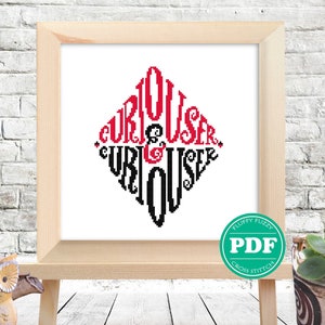 Op de afbeelding: Een kruissteekpatroon met de woorden "Curiouser and Curiouser" in een ruitvorm. De woorden zijn in zwart en rood, met "Curiouser" in rood en "and" in zwart. Het patroon is ingelijst en wordt getoond op een ezel.