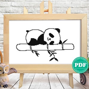 Puede incluir: Patrón de punto de cruz en blanco y negro de un panda durmiendo en una rama de bambú. El patrón está en formato PDF digital.