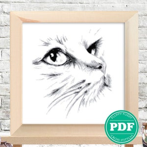 Puede incluir: Patrón de punto de cruz en blanco y negro de la cara de un gato mirando hacia la derecha. El patrón está enmarcado y se muestra en un caballete de madera. El texto "Fluffy Fuzzy PDF Cross Stitch" está en un círculo verde debajo del marco.