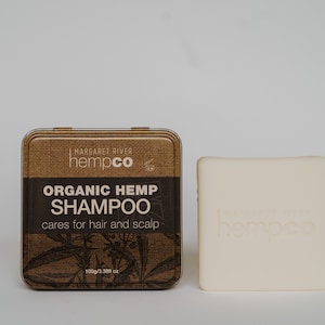 以下が含まれることがあります： 麻布の質感の茶色のブリキ缶に「MARGARET RIVER hempco ORGANIC HEMP SHAMPOO cares for hair and scalp 100g/3.38fl oz」という文字が書かれており、その隣には「hempco」という文字が浮き彫りになった白い石鹸の棒があります。