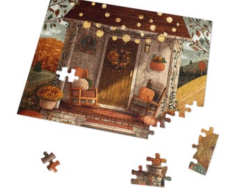 May include: A partially assembled jigsaw puzzle depicting a cozy autumn scene. The image shows a porch with pumpkins, a wreath, and string lights. The puzzle pieces are scattered around the main image, with a white background.