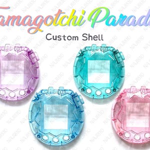 Op de afbeelding: Vier transparante Tamagotchi-schelpen in roze, blauw, teal en paars. De tekst "Tamagotchi Paradise" en "Custom Shell" staan bovenaan. Elke schelp heeft een rechthoekig scherm en knoppen.