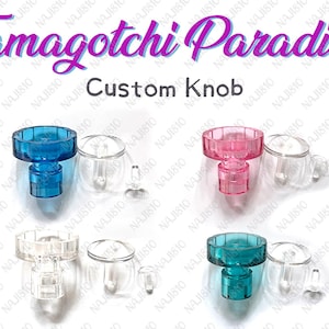 Puede incluir: Perillas personalizadas en azul, rosa, transparente y turquesa. Cada perilla tiene una parte superior circular y una base cilíndrica. El texto "Tamagotchi Paradise" y "Custom Knob" son visibles.