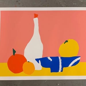 May include: A colorful still life art print featuring a white bottle with a red stopper, a blue bowl with white accents, and various fruits. The background is a salmon pink with a yellow base.