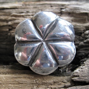 Puede incluir: Un botón de plata en forma de estrella de cinco puntas con una superficie lisa y reflectante.