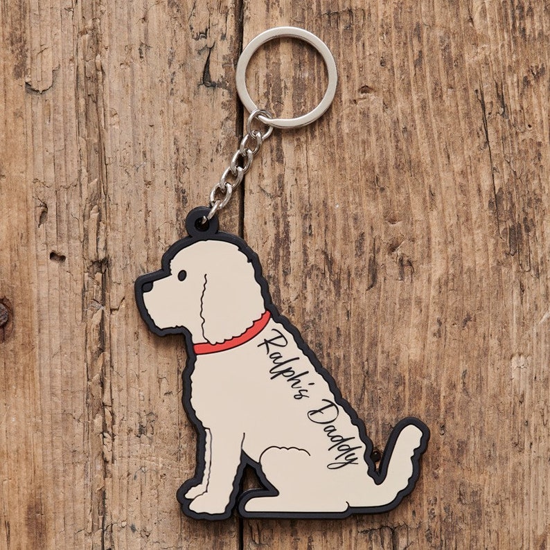 以下が含まれることがあります： クリーム色の犬の形をしたキーホルダーで、黒い輪郭と赤い首輪が付いています。キーホルダーには「Ralph's Daddy」という文字が書かれています。