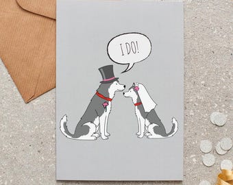 Könnte beinhalten: Graue Grußkarte mit einer Cartoon-Illustration von zwei Husky-Hunden. Einer trägt einen Zylinder, der andere einen Schleier. Eine Sprechblase sagt "I DO!". Ein brauner Umschlag und ein goldenes Band sind im Hintergrund.