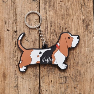 May include: A novelty keychain in the shape of a basset hound. The dog is depicted in brown, black, and white, with the name "Walter" in white script. It has a silver metal ring and chain for attaching keys.