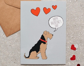 May include: A Valentine's Day card featuring a cartoon dog with a red collar and the text "Happy Valentine's Day!" in a speech bubble. The card has three orange hearts and is on a gray background.