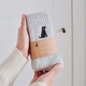 May include: Grey socks with a black dog embroidered on them. The socks are packaged with a brown label that says "Sweet Muddy Paws" and "Dogfather socks".