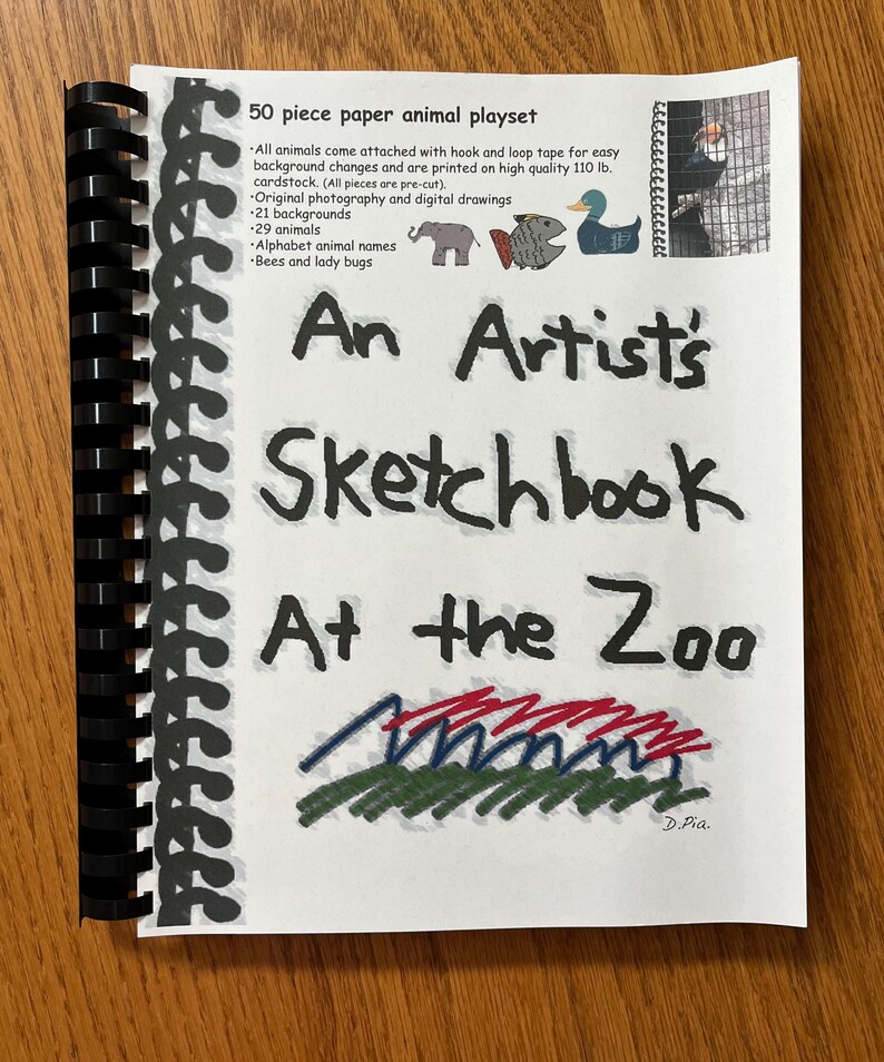 May include: A white booklet with a black spiral binding. The cover features a colorful illustration of a zoo with the title "An Artist's Sketchbook At the Zoo" and the text "50 piece paper animal playset".