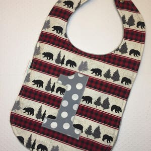 May include: A red and white plaid baby bib with a gray felt number one and a black bear print.