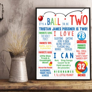 May include: A colorful printable poster celebrating a child's second birthday. The poster features the text "It's a Ball to Be Two!" and includes details about the child's favorite things, including songs, toys, books, foods, and activities. The poster also includes the child's weight and height in inches.