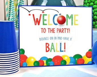 May include: A colorful welcome sign for a party with the text "Welcome to the party! Bounce on in and have a ball!" The sign is decorated with colorful balls.