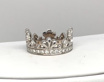 May include: A silver crown ring with a row of small diamonds around the band.