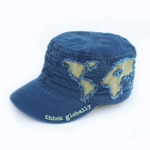 May include: A blue denim cap with a green world map embroidered on the front. The brim of the cap has the text "think globally" embroidered in green.