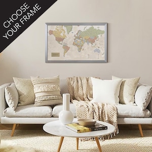 May include: A living room with a white couch and a coffee table. The couch has a white throw blanket and several pillows. A framed world map hangs on the wall above the couch.