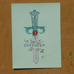 Puede incluir: Una ilustración dibujada a mano de una espada azul y plateada con un ojo rojo en el centro de la empuñadura. El texto "Eye of Thundera" está escrito debajo de la espada.