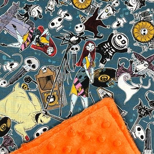 Puede incluir: Una tela azul con un patr&oacute;n repetido de personajes de Pesadilla Antes de Navidad. Los personajes incluyen a Jack Skellington, Sally y Oogie Boogie. La tela est&aacute; cubierta con una manta peluda de color naranja brillante.