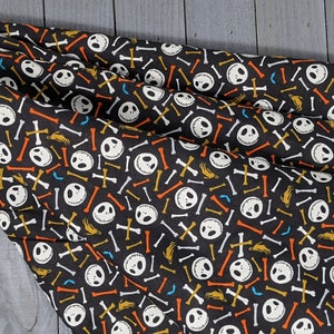 May include: Black fabric with a repeating pattern of white Jack Skellington faces, orange and yellow bones, and white crossbones.