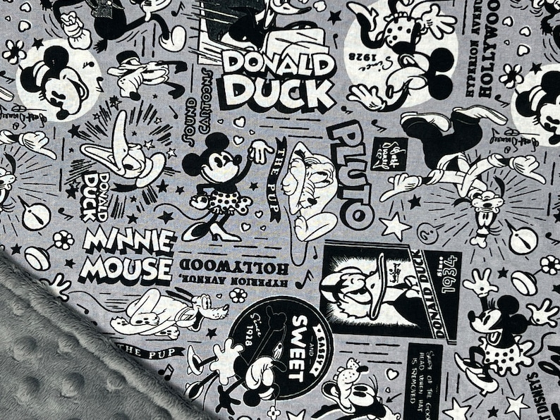 Peut inclure: Tissu gris avec un imprim&eacute; de dessins anim&eacute;s en noir et blanc repr&eacute;sentant Mickey Mouse, Minnie Mouse, Donald Duck et Pluto. Le motif comprend des &eacute;l&eacute;ments textuels tels que "Donald Duck", "Minnie Mouse" et "Pluto", ainsi que des &eacute;toiles et des notes de musique.