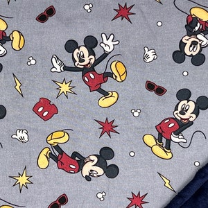 Pu&ograve; includere: Tessuto grigio con un motivo ripetitivo di Topolino in varie pose. Lo sfondo presenta stelle rosse, fulmini gialli e pois bianchi. Il tessuto &egrave; abbinato a un tessuto blu scuro e peloso.