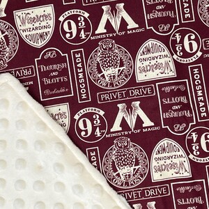 May include: A burgundy fabric with a white repeating pattern of Harry Potter themed images. The images include the Hogwarts Express Platform 9 3/4, the Ministry of Magic, the Owl Post, Flourish and Blotts, Wiseacres Wizarding Equipment, and Privet Drive.