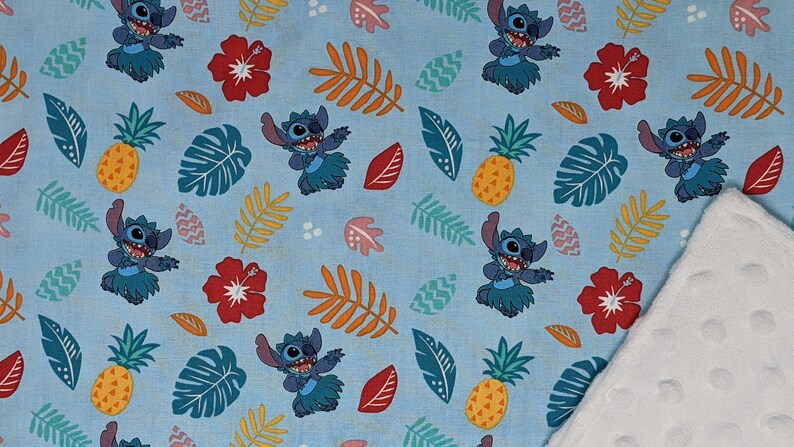 May include: A blue and white fabric with a repeating pattern of Stitch from Lilo & Stitch wearing a grass skirt, pineapples, and tropical leaves.