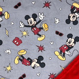 Pu&ograve; includere: Un tessuto grigio con un motivo ripetitivo di Topolino in varie pose. Il tessuto &egrave; abbinato a un tessuto rosso strutturato.